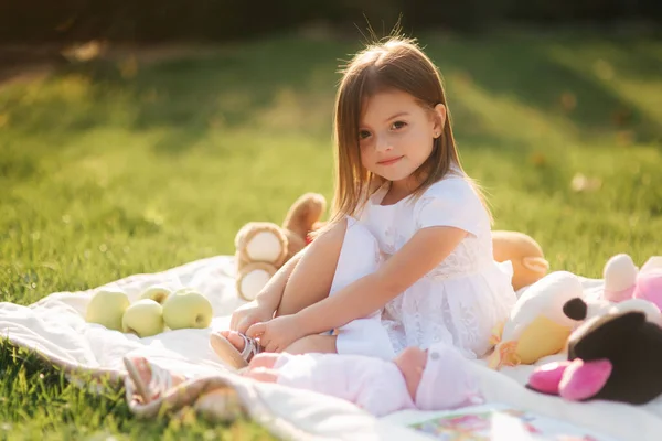 Schattig klein meisje zit buiten op de ruit en leest het boek. gelukkig glimlach baby meisje tijd doorbrengen op achtertuin in zonsondergang — Stockfoto