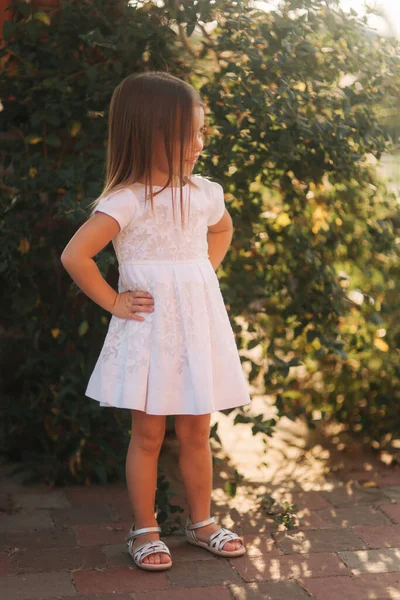 Hermosa niña en vestido blanco caminando al aire libre en la espalda yaer de casa. Chico feliz — Foto de Stock