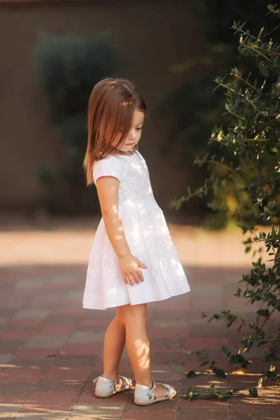 Όμορφο κοριτσάκι σε λευκό φόρεμα με τα πόδια σε εξωτερικούς χώρους στην πλάτη yaer του σπιτιού. Χαρούμενο παιδί — Φωτογραφία Αρχείου