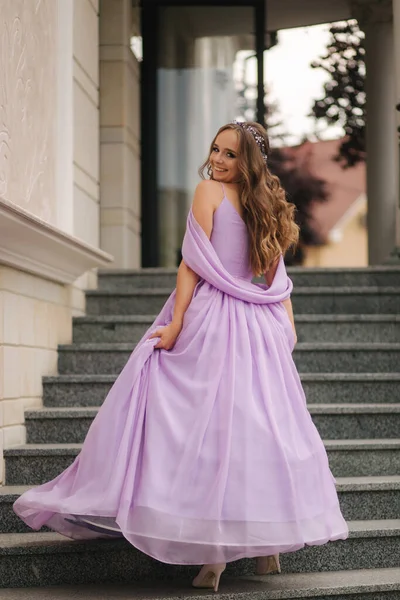 Vacker ung flicka i kväll lavendel klänning stå i trappor av restaurang — Stockfoto