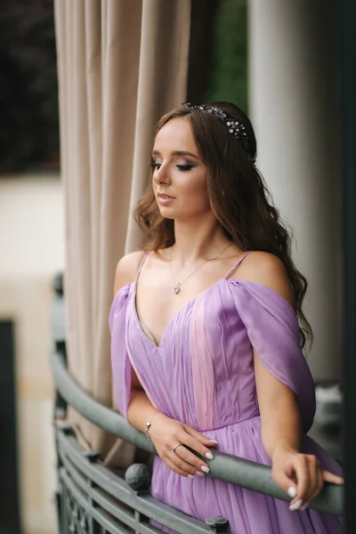 Retrato de una hermosa mujer joven de pie en la terraza en vestido de noche de lavanda. Maquillaje elegante —  Fotos de Stock