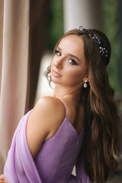 Retrato de una hermosa mujer joven de pie en la terraza en vestido de noche de lavanda. Maquillaje elegante —  Fotos de Stock