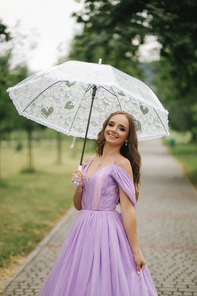 Junges Model im Abendkleid im Freien mit Regenschirm unterwegs — Stockfoto