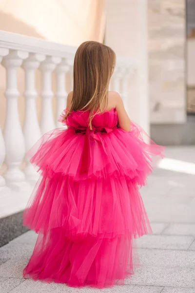 Achteraanzicht van schattig klein meisje in roze pluizige jurk wandelen door het restaurant — Stockfoto