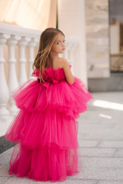 Rückansicht des entzückenden kleinen Mädchens im rosafarbenen flauschigen Kleid, das am Restaurant vorbeiläuft — Stockfoto