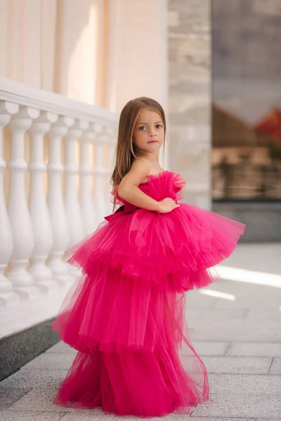 Adorable little girl model in pink fluffy dress walkin outdoors by the restaurant. Happy little kid — Stock Photo, Image