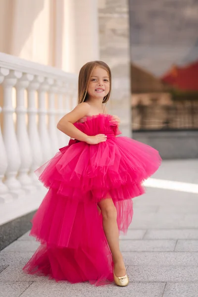 Αξιολάτρευτο μικρό κορίτσι μοντέλο σε ροζ χνουδωτό φόρεμα walkin έξω από το εστιατόριο. Χαρούμενο παιδάκι. — Φωτογραφία Αρχείου