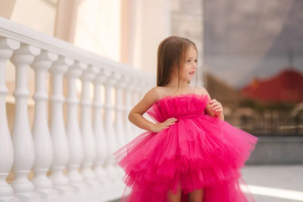 Adorable little girl model in pink fluffy dress walkin outdoors by the restaurant. Happy little kid. Space for text — Stock Photo, Image