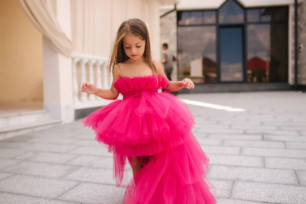 Adorable little girl model in pink fluffy dress walkin outdoors by the restaurant. Happy little kid — Stock Photo, Image