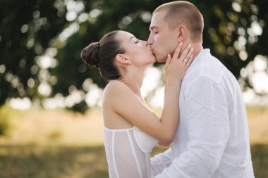 Büyük ağacın önünde gelini öpen damadın portresini yakından çek. Yan görünüm