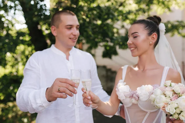 Jeune couple de marié et mariée debout outdors et boire du champagne — Photo