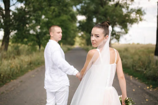 Fiatal és gyönyörű menyasszony jóképű vőlegény ölelés egymást csók és mosoly. A boldog házaspár portréja — Stock Fotó