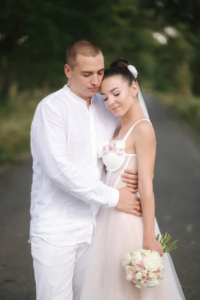 Junge und schöne Braut mit schönen Bräutigam umarmen einander küssen und lächeln. Glückliches Hochzeitspaar im Porträt — Stockfoto