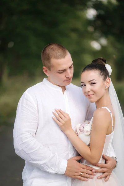 Mladá a krásná nevěsta s krásným ženichem objímat navzájem polibek a úsměv. Portrét šťastného manželského páru — Stock fotografie