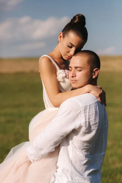 Novomanželé chodí do terénu. Ženich objetí nevěsta po svatebním obřadu — Stock fotografie