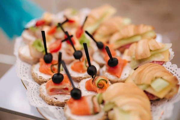 Sandwich de croissant con jamón y tartalets con pescado rojo y aceituna en plato al aire libre. Fiesta en terraza — Foto de Stock