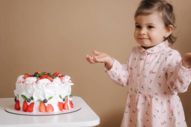 Şirin küçük bir kız ve enfes bir doğum günü pastasının yanında duran iri yarı bir kız. On sekiz aylık kız çok mutlu ve gülüyor. Vejetaryen yemeği. Laktozsuz ve glütensiz..