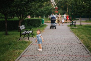 Parkta yürüyen mutlu küçük çocuk. Kot giyen küçük kız.