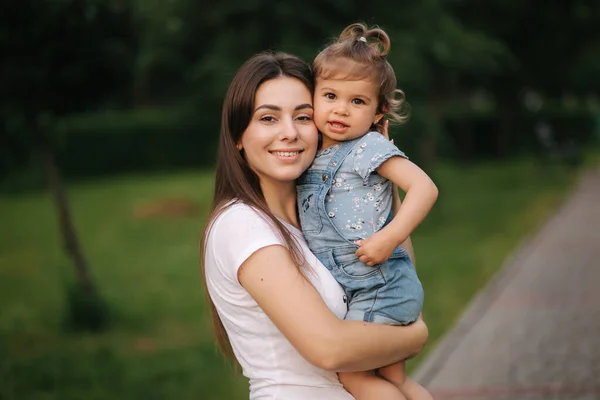 Portretul unei mame frumoase cu o fetiță adorabilă. O familie fericită în aer liber. Fiica imbratisare mama — Fotografie, imagine de stoc