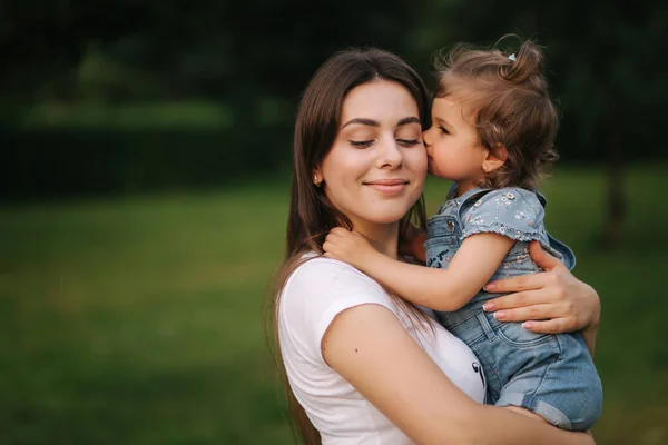 Portretul unei mame frumoase cu o fetiță adorabilă. O familie fericită în aer liber. Fiica da sarut la mama — Fotografie, imagine de stoc