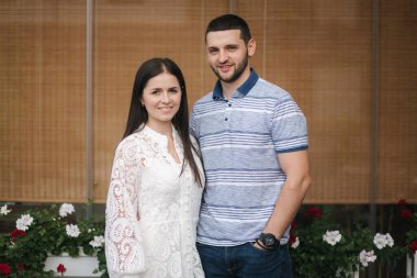 Kocasıyla birlikte dışarıda duran güzel genç bir kadının portresi.