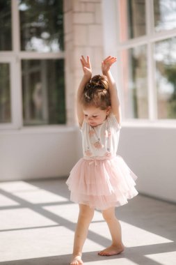 Stüdyoda fotoğrafçıya poz veren üç yaşında tatlı bir kız. Güzel küçük kız dansı.