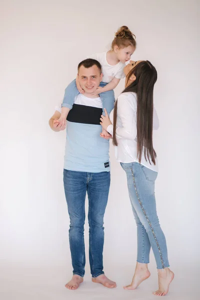 Adorável menina senta-se no pescoço dos pais. Mãe beijo filha — Fotografia de Stock