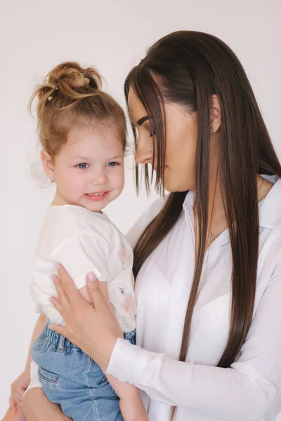 Ritratto di bambina con mamma in studio. Fondo bianco — Foto Stock