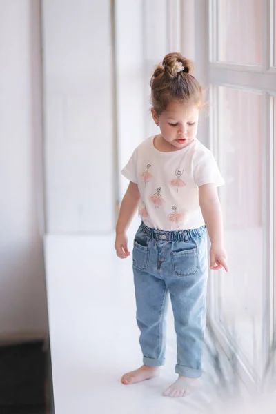 Adorable niña pequeña caminar a través del alféizar de la ventana en el estudio — Foto de Stock