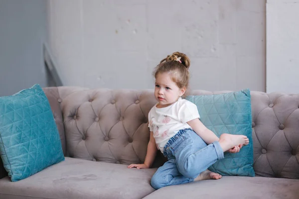 아름다운 어린 소녀의 모습이 스튜디오 소파에 앉아 있다 — 스톡 사진