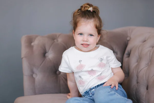 Portret van een mooi klein meisje zit op de bank in de studio — Stockfoto