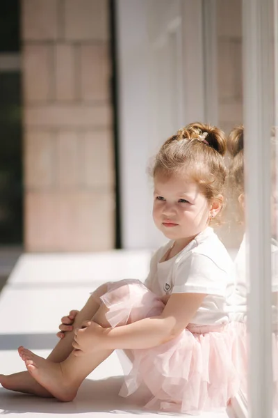 Χαριτωμένο κοριτσάκι τριών ετών με φόρεμα που ποζάρει για φωτογράφο στο στούντιο. Το όμορφο κοριτσάκι κάθεται στο περβάζι του παραθύρου — Φωτογραφία Αρχείου