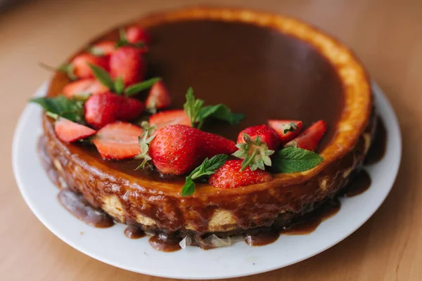 Torta de morango saborosa decorada com folhas de hortelã na mesa de madeira. Esmalte de caramelo em cima da torta. Pequeno-almoço Vegan. Lactose e sem glúten — Fotografia de Stock