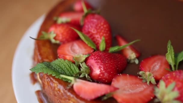 Tarta de fresa deliberada decorada con hojas de menta sobre una mesa de madera. Esmalte de caramelo en la parte superior de la tarta. Desayuno vegano. Lactosa y sin gluten — Vídeos de Stock