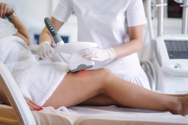 Çekici kadın dinlenirken beyaz eldivenli kozmetik uzmanı midesine radyasyon kaldırma prosedürü uyguluyor. Klinikteki güzel kadın. Tıbbi maskeli güzellik uzmanı.