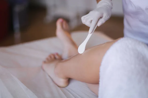 Ung kvinna kosmetolog i mask applicerar kontaktgel på benet av en kvinna för laser hårborttagning i medicinsk klinik. Närbild — Stockfoto