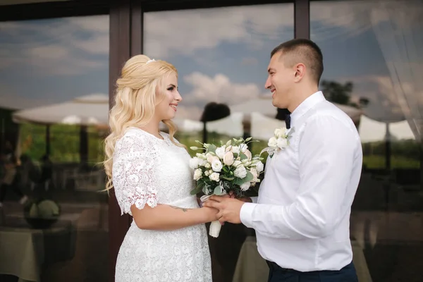 Heureux jeunes mariés marchant à l'extérieur. Femme aux cheveux blonds et jeune homme en chemise blanche — Photo