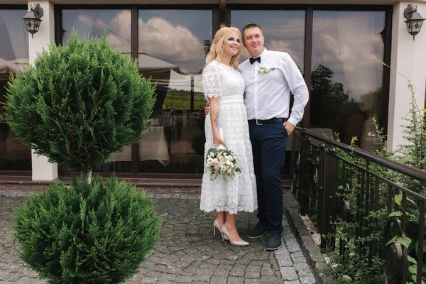 Gelukkige pasgetrouwden die buiten lopen. Blond haar vrouw en jonge man in wit shirt — Stockfoto