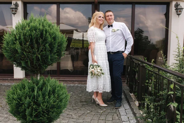 Heureux jeunes mariés marchant à l'extérieur. Femme aux cheveux blonds et jeune homme en chemise blanche — Photo