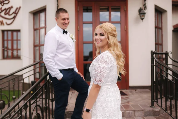 Felizes recém-casados a andar ao ar livre. Mulher de cabelo loiro e jovem de camisa branca — Fotografia de Stock