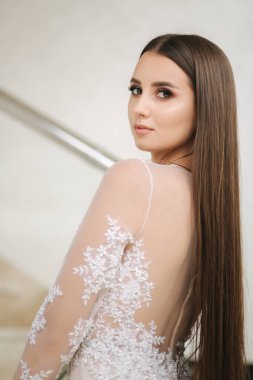Gelin gibi beyaz elbiseli, gece makyajlı güzel bir genç kadının portresi.