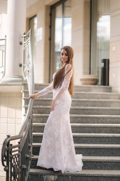Aantrekkelijke jonge vrouw in mooie jurk staan op de trap — Stockfoto