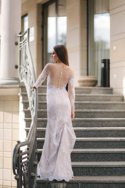 Atractiva joven mujer en hermoso vestido de pie en las escaleras — Foto de Stock