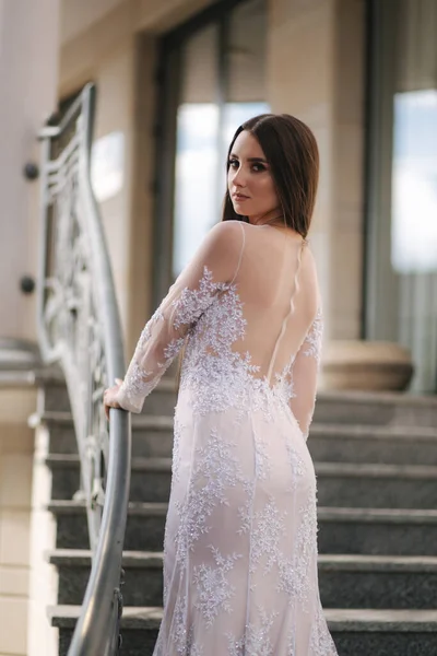 Atractiva joven mujer en hermoso vestido de pie en las escaleras — Foto de Stock