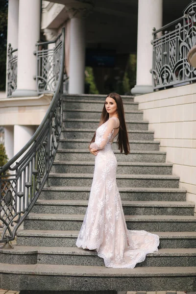 Modelo lindo em vestido de noiva stand na escada por grande restaurante — Fotografia de Stock