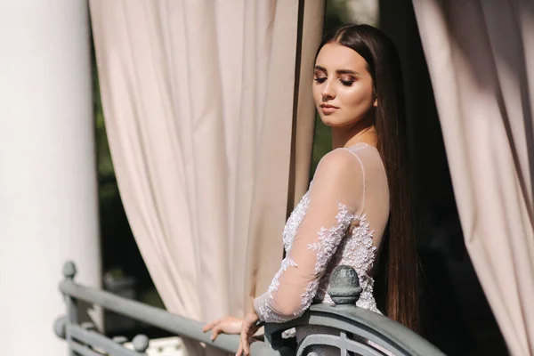 Hermosa joven modelo en la noche drees posando al fotógrafo por la ventana grande — Foto de Stock