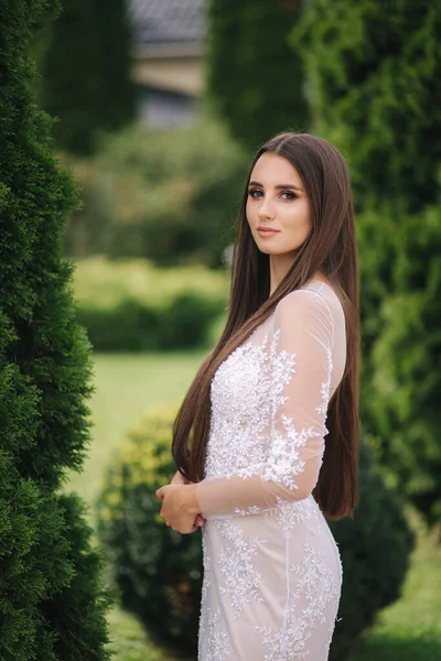 Splendida giovane donna in abito da sposa stan all'aperto di fronte a alberi verdi — Foto Stock