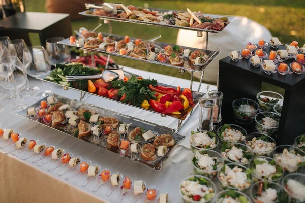 Grote tafel met verschillende luxe snacks op het luxe feest buiten bij zonsondergang — Stockfoto