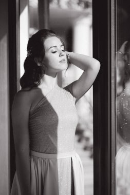 Lüks restoranın büyük penceresinde duran zarif genç bayan.