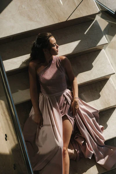 Muhteşem elbiseli zarif bir kadın lüks bir restoranın merdivenlerinde yatıyor. — Stok fotoğraf